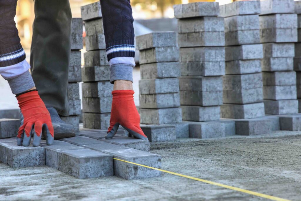 Installing paving construction stone block sidewalk of a road working interlock construction site